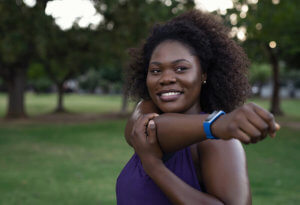 Portrait of a happy, curvy African American woman stretching her arms while exercising outside.